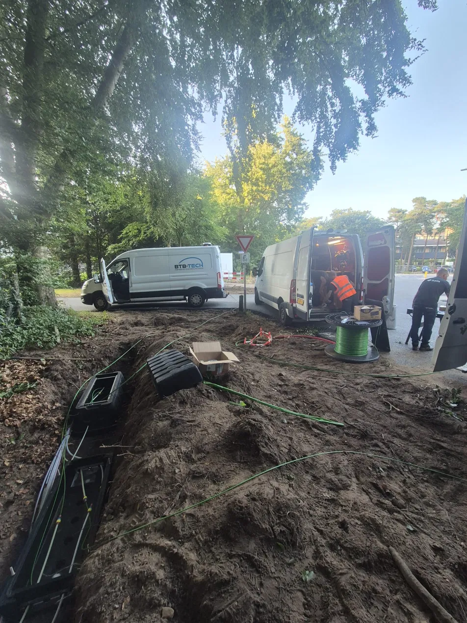 BTB-Tech bestelbussen en monteurs bij open kabelsleuf met glasvezelkabels tijdens storingsherstel Harderwijk